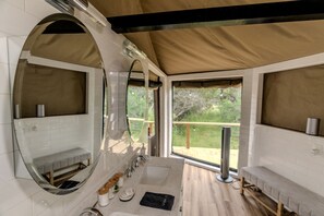 A modern bathroom with a large mirror, a sink, and a window overlooking a deck.