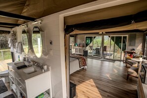 Un dormitorio moderno con una cama grande, un baño con lavamanos doble y un balcón con mobiliario exterior.