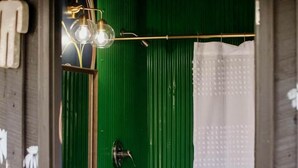 Un baño con lavamanos blanco, grifo dorado y pared verde.