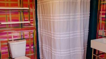 A bathroom with a patterned wall, a white toilet, a shower curtain, and a tiled floor.