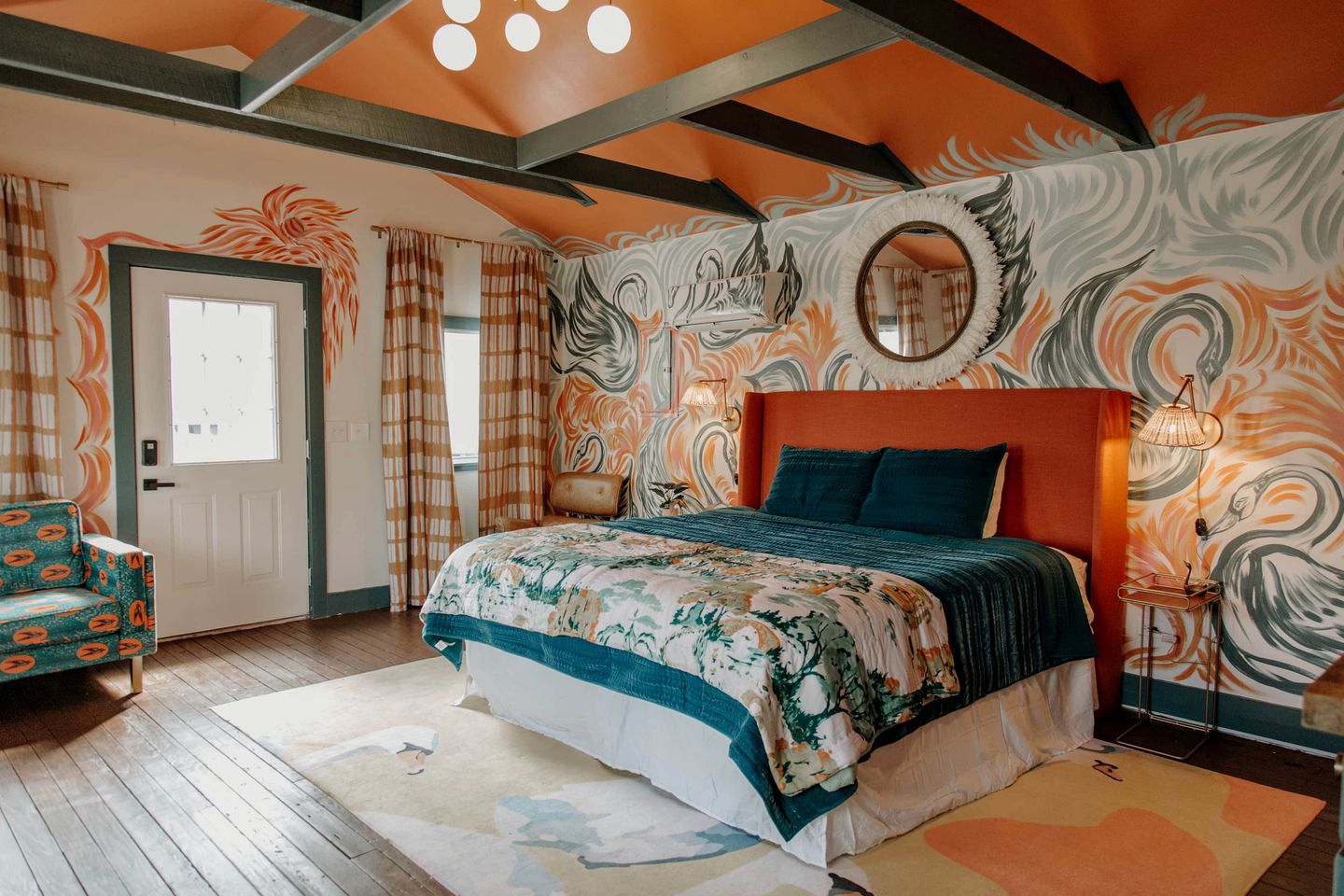 A bedroom with a bed, a chair, a door, and a wall with a swirl pattern.