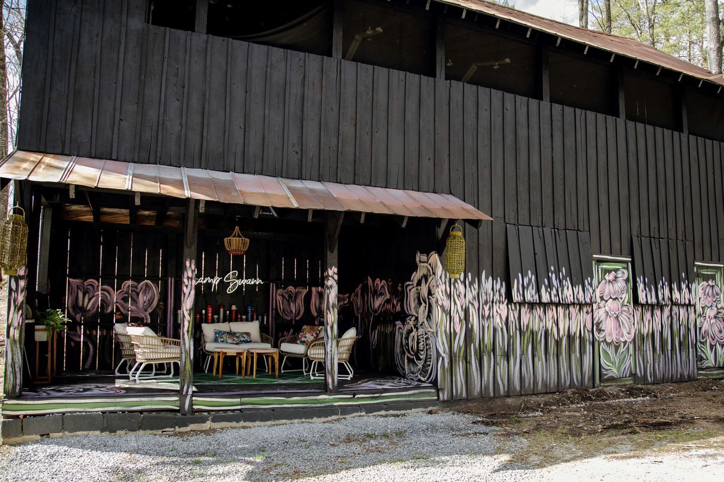 Ein rustikales Holzgebäude mit einer Veranda, Sitzgelegenheiten im Freien und einem Wandgemälde.