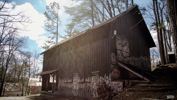 A rustic wooden building with a sloped roof, surrounded by trees. - Chic and Cozy: Romantic Glamping at Its Finest in Tennessee (Tracy City)