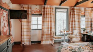 A room with a bed, a dining table with chairs, a TV, and a window with curtains. - Chic and Cozy: Romantic Glamping at Its Finest in Tennessee (Tracy City)
