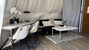 A tented accommodation with a dining area, seating, and a small table.