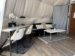 A tented accommodation with a dining area, seating, and a small table. - Geo Dome 2 (Burnet)
