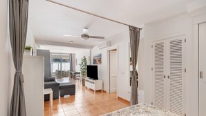 Ein Hotelzimmer mit Bett, Vorhängen, Fernseher, Essbereich und Blick ins Freie.
