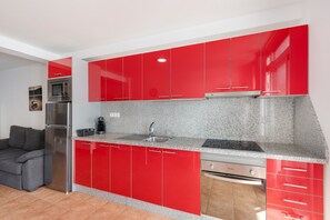 A modern kitchen with red cabinets, stainless steel appliances, and a granite countertop. - Vacation Studio 'Vv Timón' with Mountain View, Wi-Fi and Air Conditioning (Puerto de Mogán)