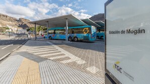 Ein Busbahnhof mit Unterstand, einem Bus und einem Schild mit der Aufschrift 'Estación de Mogán'.