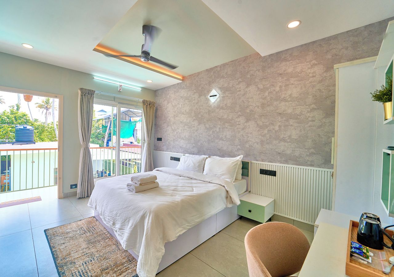 Een moderne slaapkamer met een groot bed, een plafondventilator, uitzicht op de omgeving en een klein bureau met een waterkoker.
