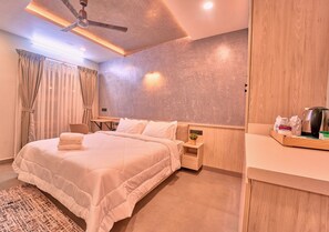 A modern bedroom with a bed, bedside tables, a desk, and a ceiling fan. - Kayal Cove Resort by VOYE HOMES (Alappuzha)