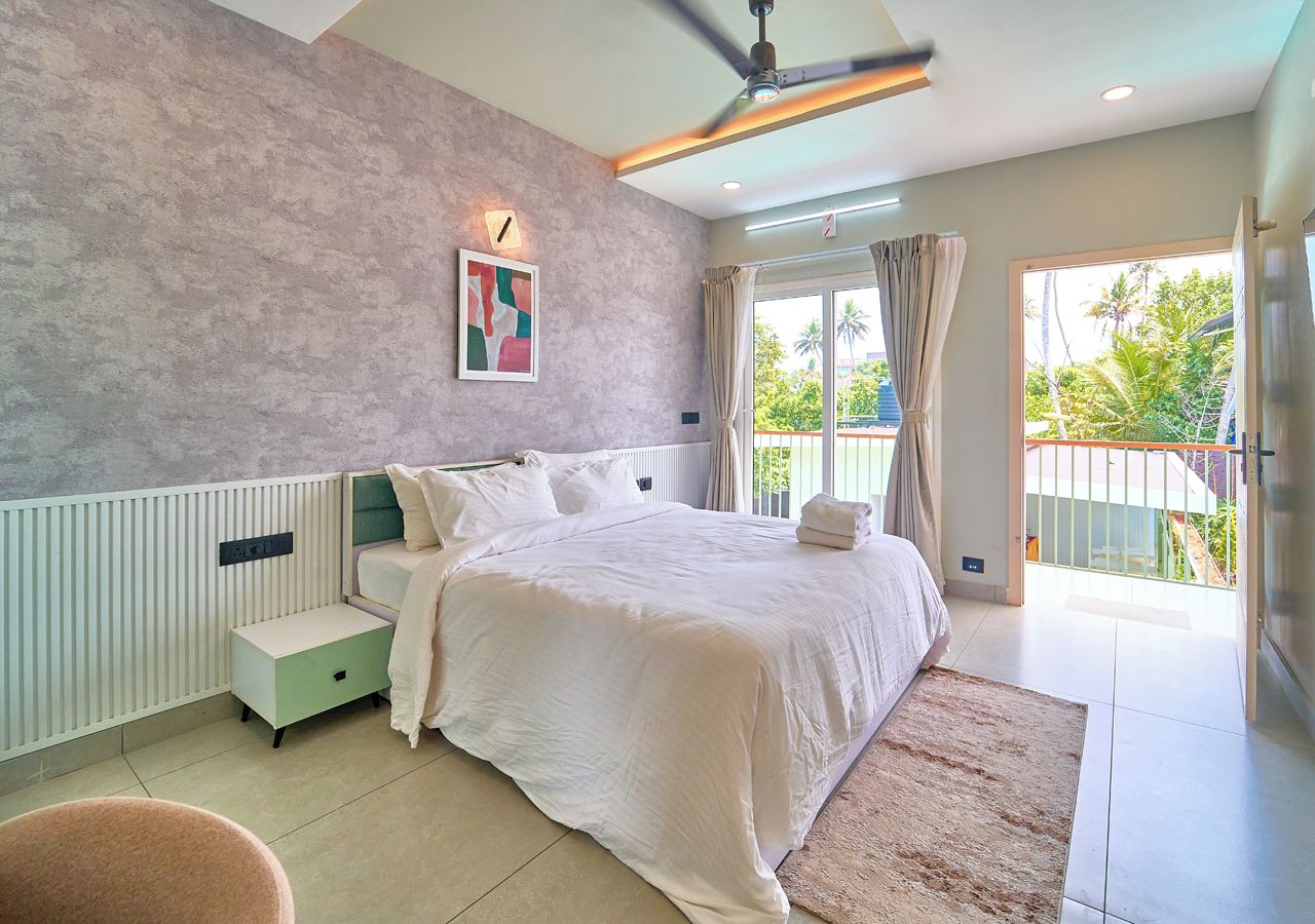 A bedroom with a bed, bedside table, and a view of the outdoors.