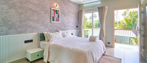 A bedroom with a bed, bedside table, and a view of the outdoors.