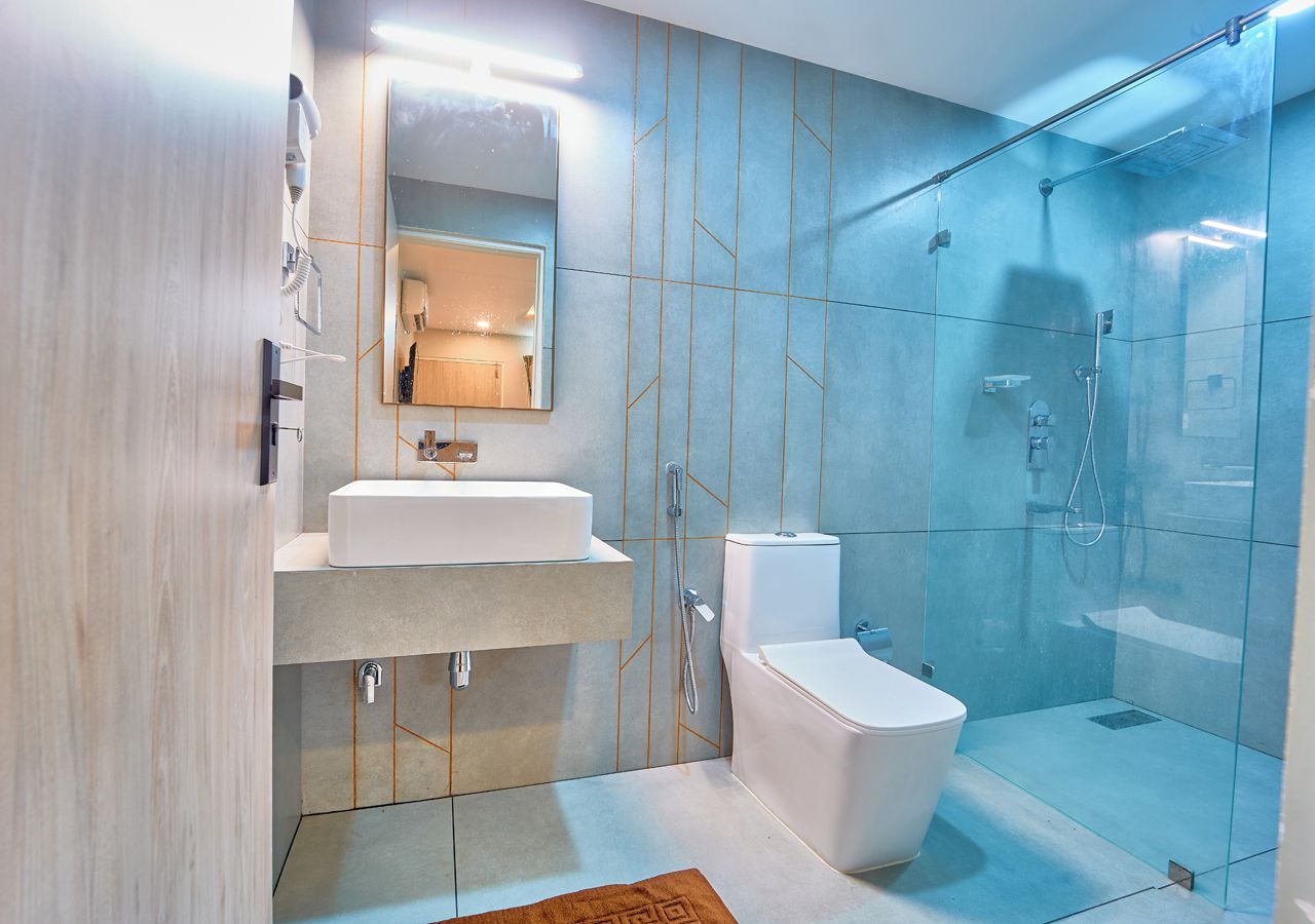 Un baño moderno con cabina de ducha de vidrio, inodoro blanco y tocador con espejo.