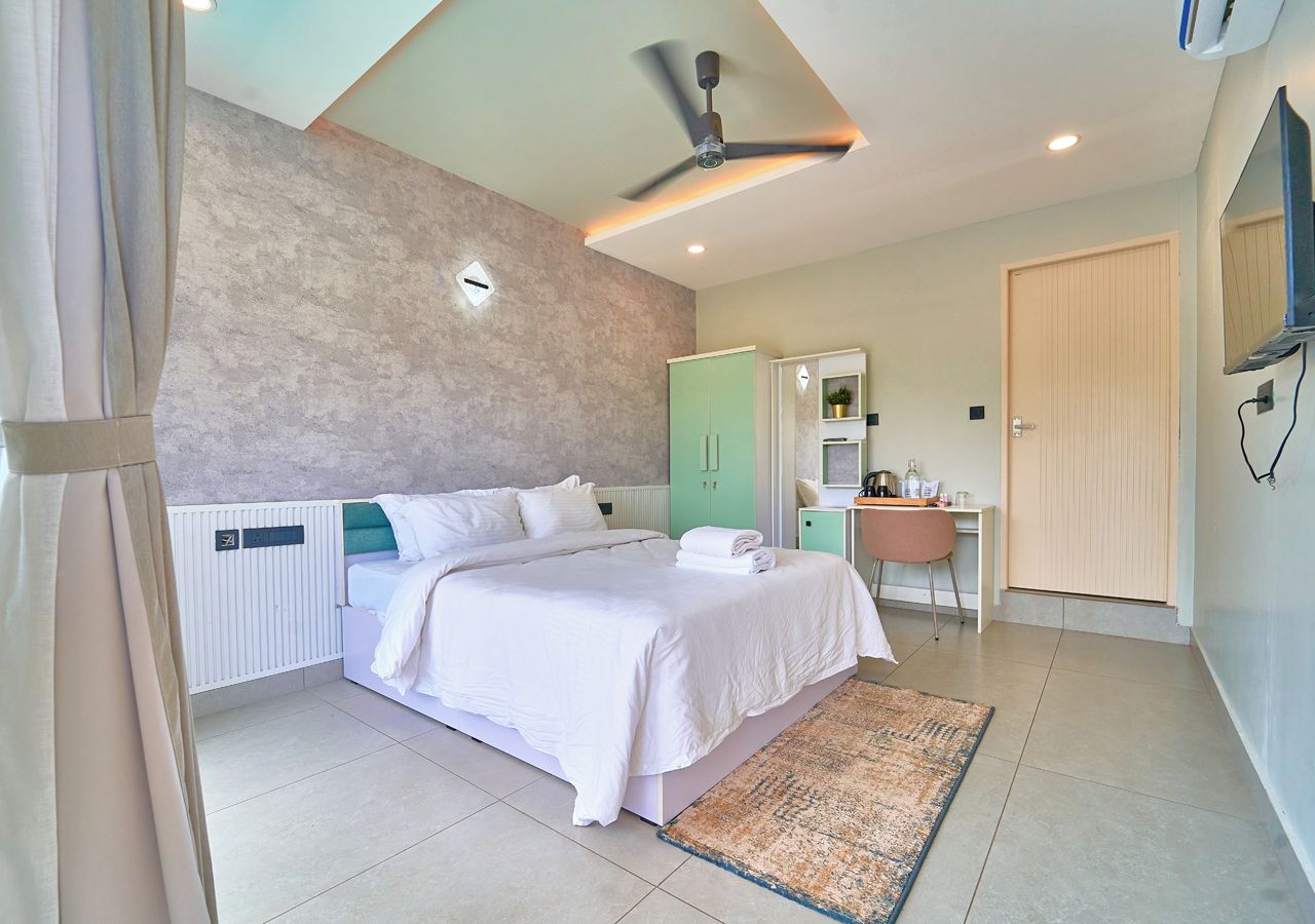 Ein Schlafzimmer mit einem Bett, einem Schreibtisch, einem Stuhl, einer Heizung, einem Deckenventilator und einer Tür.