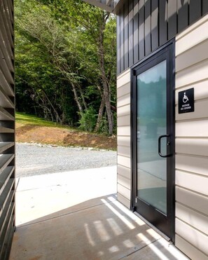 A building entrance with a glass door, a handicap sign, and a concrete path leading to a gravel area.