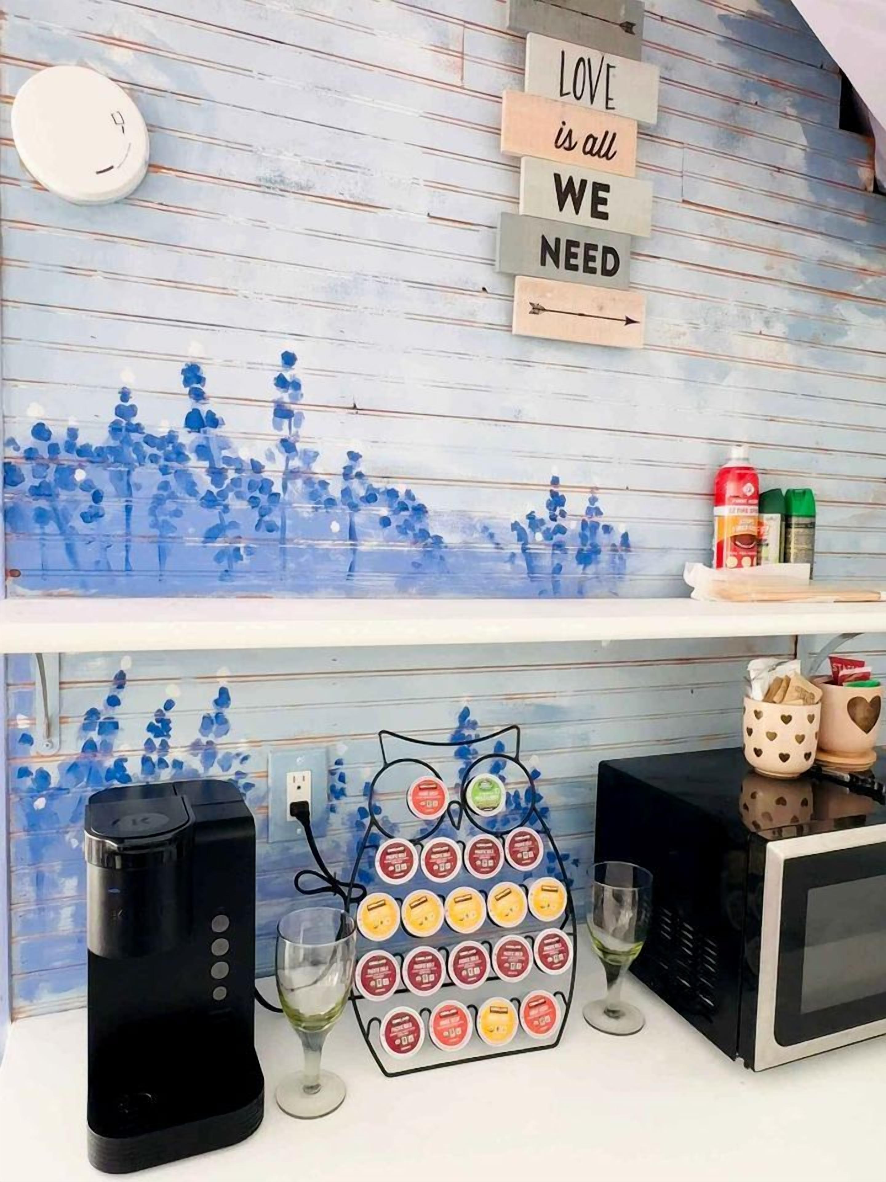 A kitchen counter with a coffee maker, wine glasses, and a decorative owl-shaped container holding tea bags.