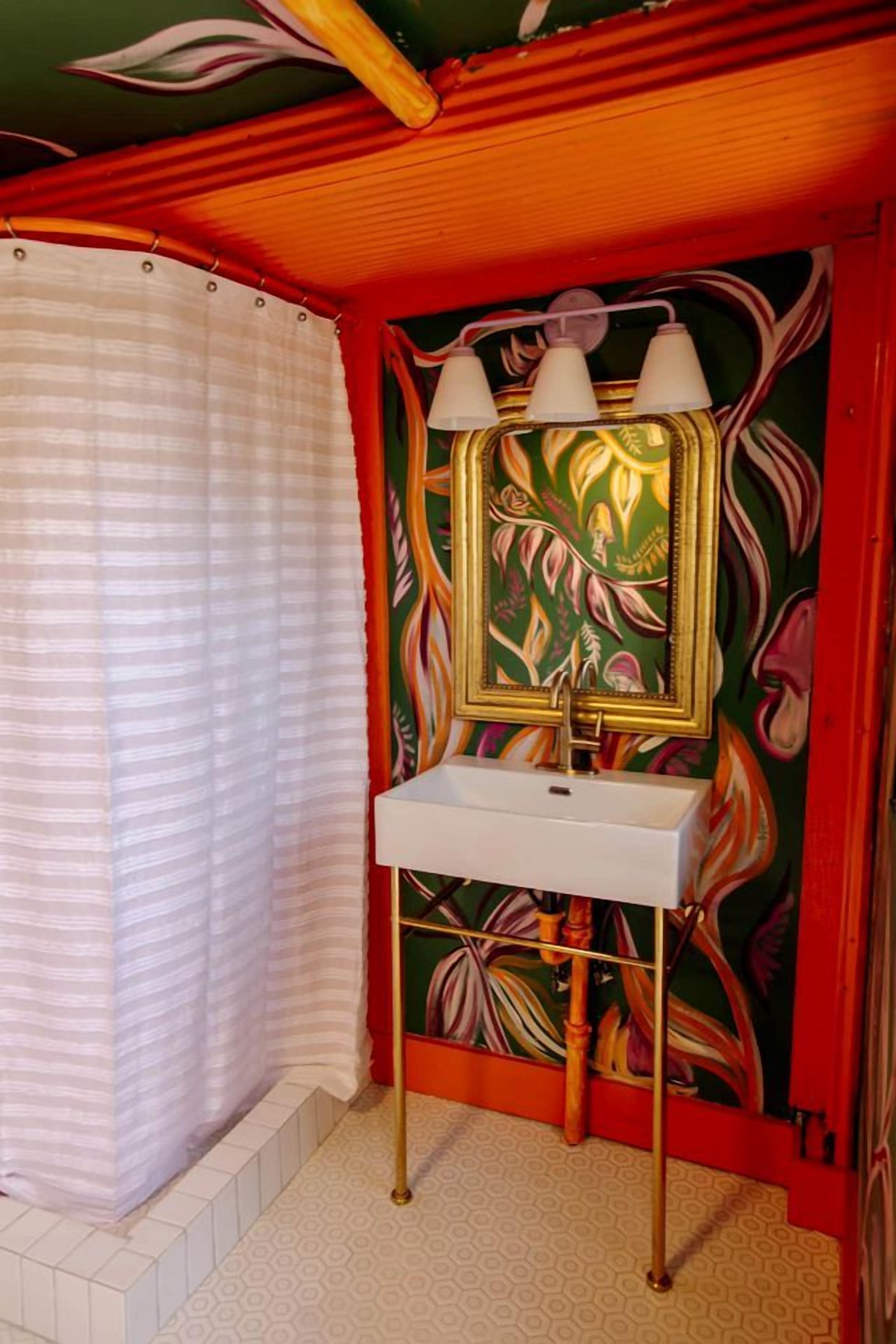 Une salle de bain avec un lavabo blanc, un miroir et un rideau de douche.