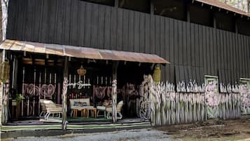 Um edifício de madeira rústica com varanda coberta, área de estar ao ar livre e um mural na parede.