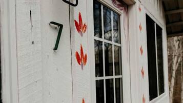 Ein weißes Gebäude mit der Aufschrift '7', ein Fenster mit Vorhang und eine hölzerne Bank davor.
