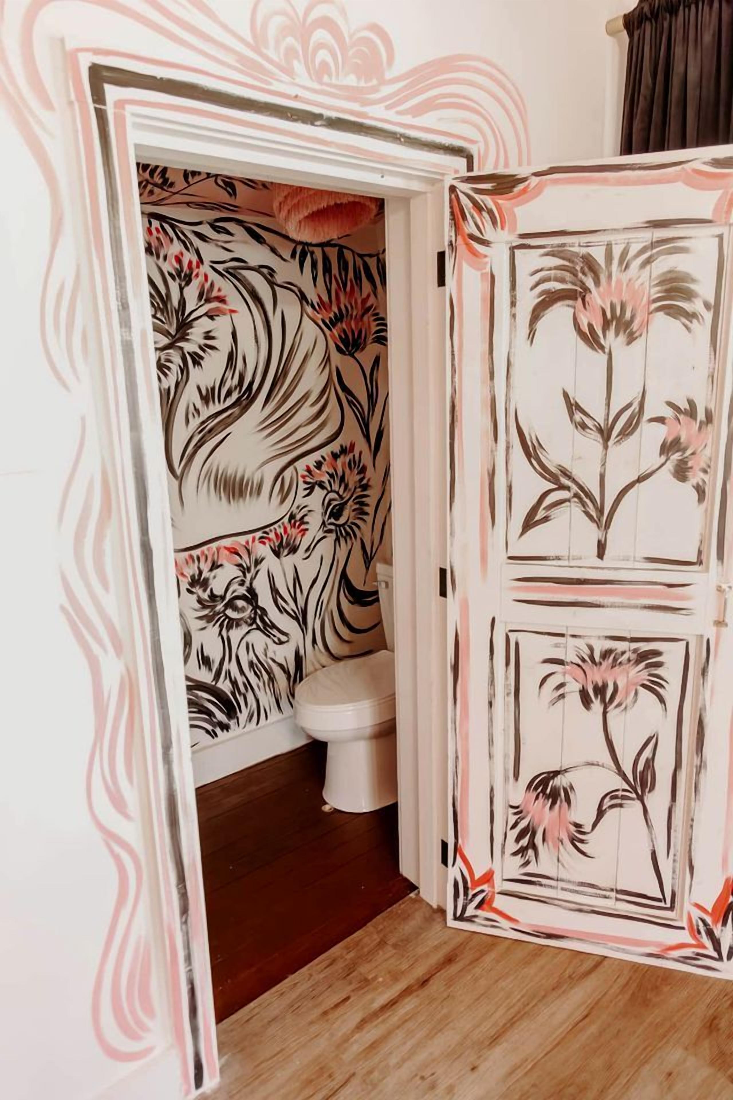 A bathroom with floral wallpaper, a white toilet, and a wooden floor.