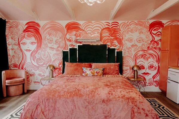 A bedroom with a large bed, a chair, a nightstand, and a dresser.