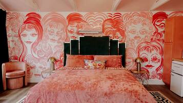 A bedroom with a large bed, a chair, a nightstand, and a dresser.