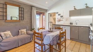 A compact living space with a dining table, sofa, kitchen area, and a large mirror.