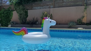 A swimming pool with a unicorn float.