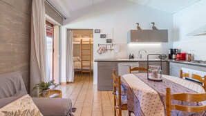 A compact living space with a kitchenette, a dining area, and a bedroom with a ladder.