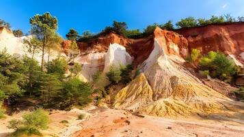 A natural landscape with a prominent rock formation, trees, and a clear sky.
