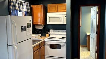 A kitchen with wooden cabinets, a white refrigerator, a stove, and a microwave.