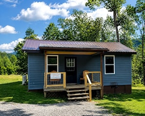 A small, single-story cabin with a porch, a sign indicating it is a campground cottage, and a gravel driveway. - Pet-Friendly Cabin in North Carolina for Amazing Getaways in the Mountains (Spruce Pine)
