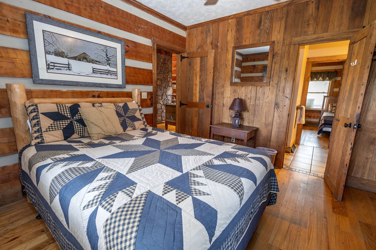 Ein Schlafzimmer mit einem großen Bett, Holzwänden, einem Steinkamin und einem gerahmten Bild an der Wand.