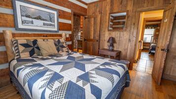 Ein Schlafzimmer mit einem großen Bett, Holzwänden, einem Steinkamin und einem gerahmten Bild an der Wand.