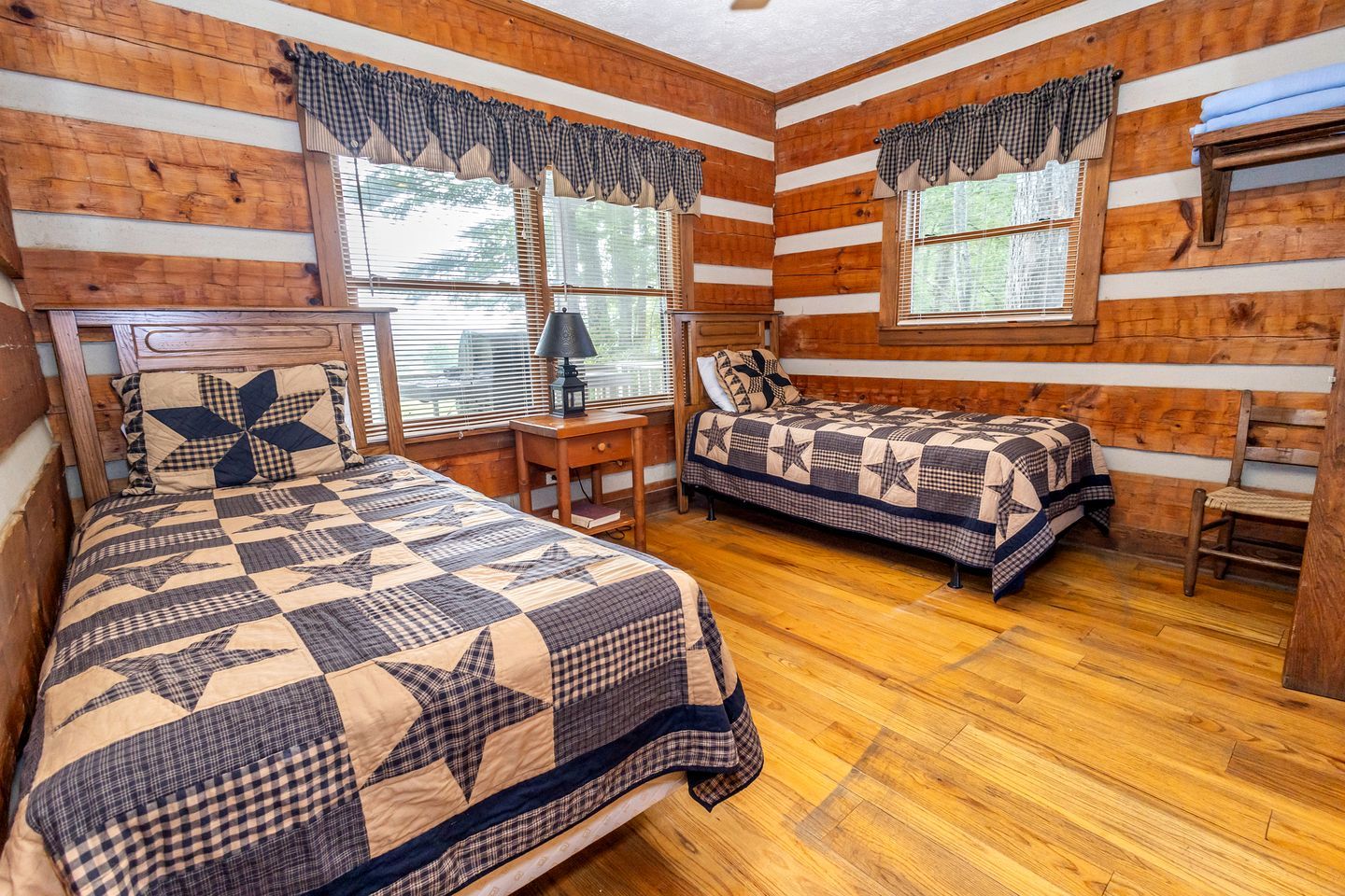 A cabin-style room with two beds, wooden walls, and a wooden floor.