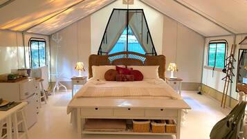 A bedroom with a bed, bedside tables, a window, and a hanging chair.