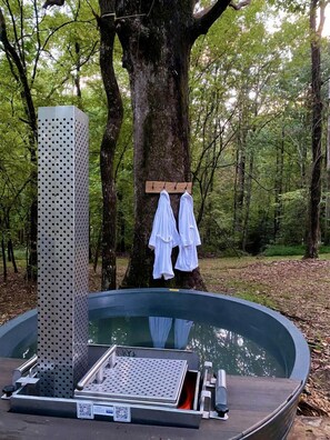 A hot tub with a metal frame, a wooden bench, and a metal platform.