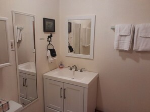 A bathroom with a white sink, a mirror, and two towels hanging on the wall.
