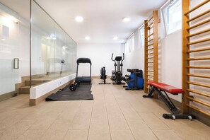 Une salle de sport équipée de matériel d’exercice, d’un banc et dotée d’un mur en verre.