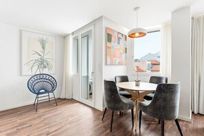 Un coin repas avec une table ronde et six chaises, une chaise bleue, un tableau et une vue à travers une porte vitrée.