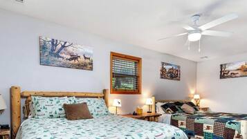 A bedroom with a bed, two bedside tables, a ceiling fan, and wall art.