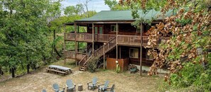 A wooden cabin with a balcony, a covered porch, and a picnic table.