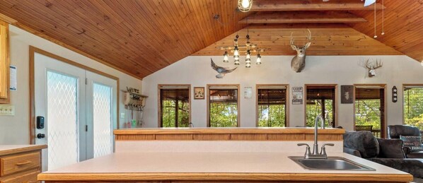 Une cuisine dotée d’un grand îlot central, d’un plafond en bois et ornée de bois de cerf au mur.
