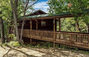 A wooden cabin with a covered porch and a wooden deck.