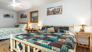 A room with two beds, a ceiling fan, and wall art.