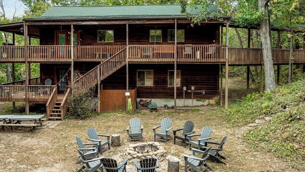 A cabin with a deck, outdoor seating, and a fire pit.