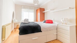 A bedroom with a bed, bedside tables, a dresser, a radiator, and a window with curtains. - Your Home in the Heart of Zaragoza (Zaragoza)