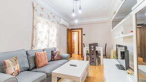 A modern living room with a grey sofa, a white coffee table, and a dining area with a white table and chairs. - Your Home in the Heart of Zaragoza (Zaragoza)