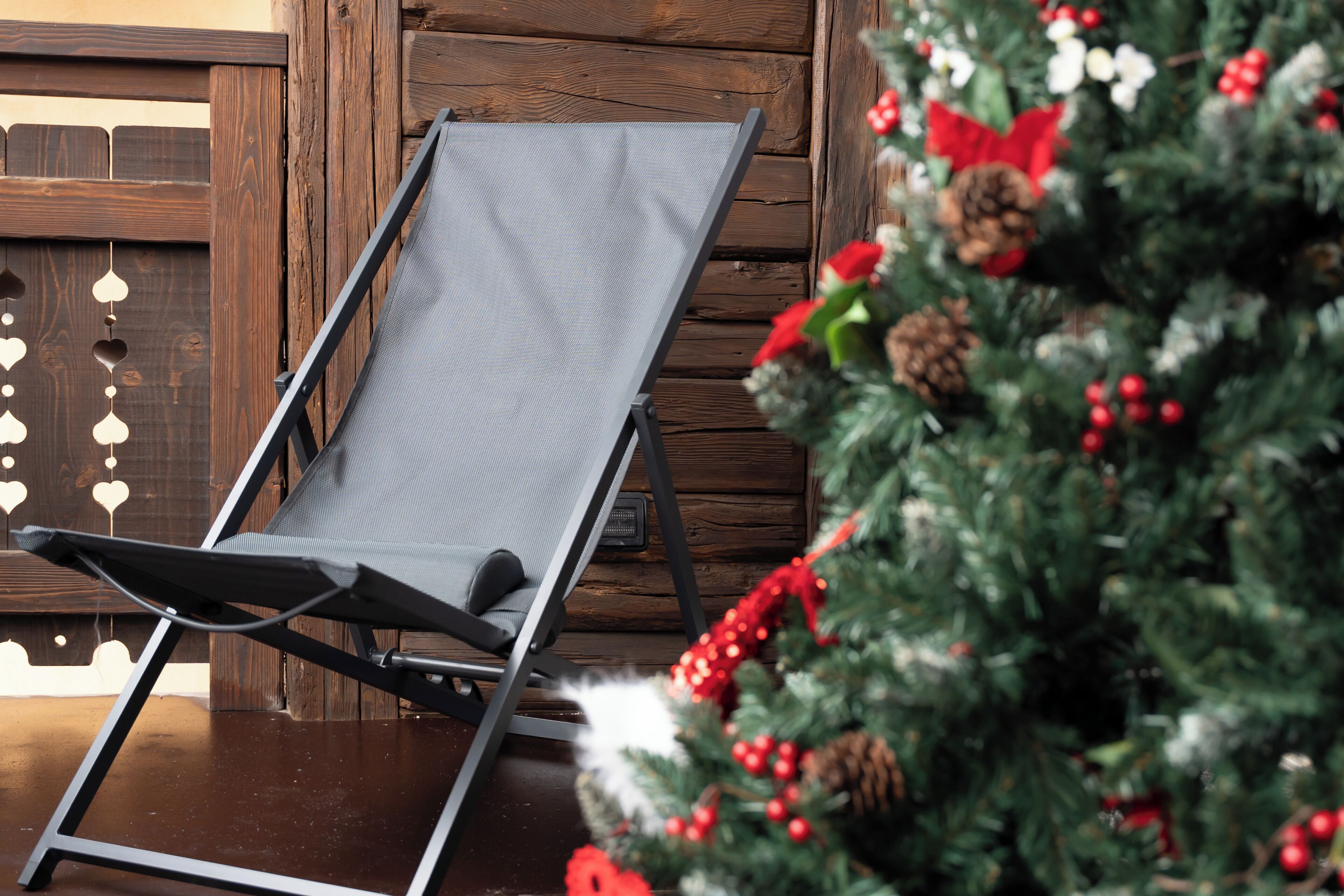 A lounge chair in a wooden room with a decorated Christmas tree.